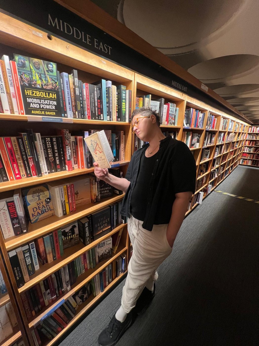 Kathy Ahfid reading in the Middle East section of a bookshop, Oxford, 2026